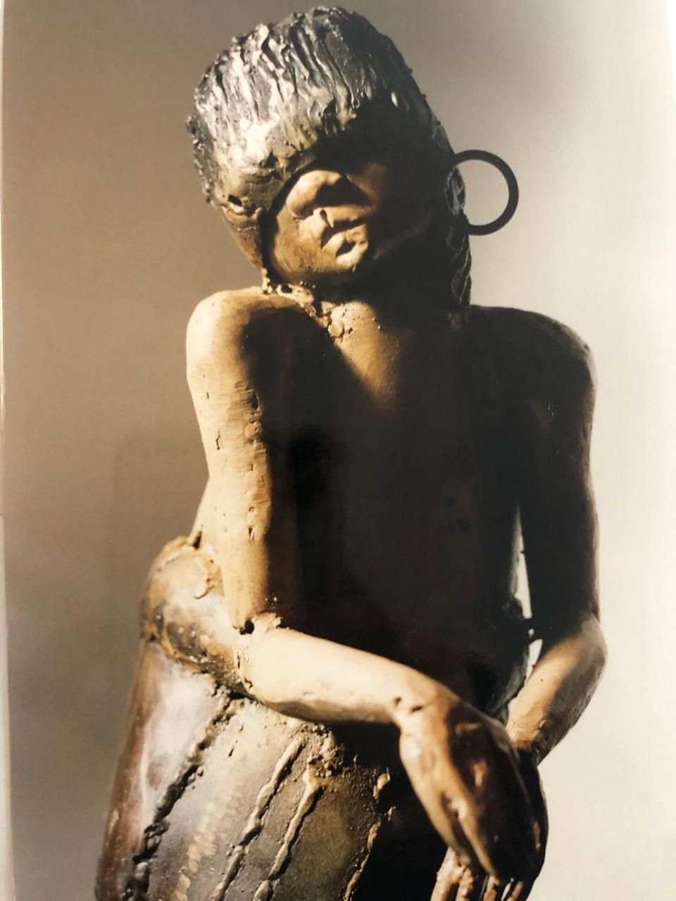 Busto de perfil de una figura femenina con un gran arete circular