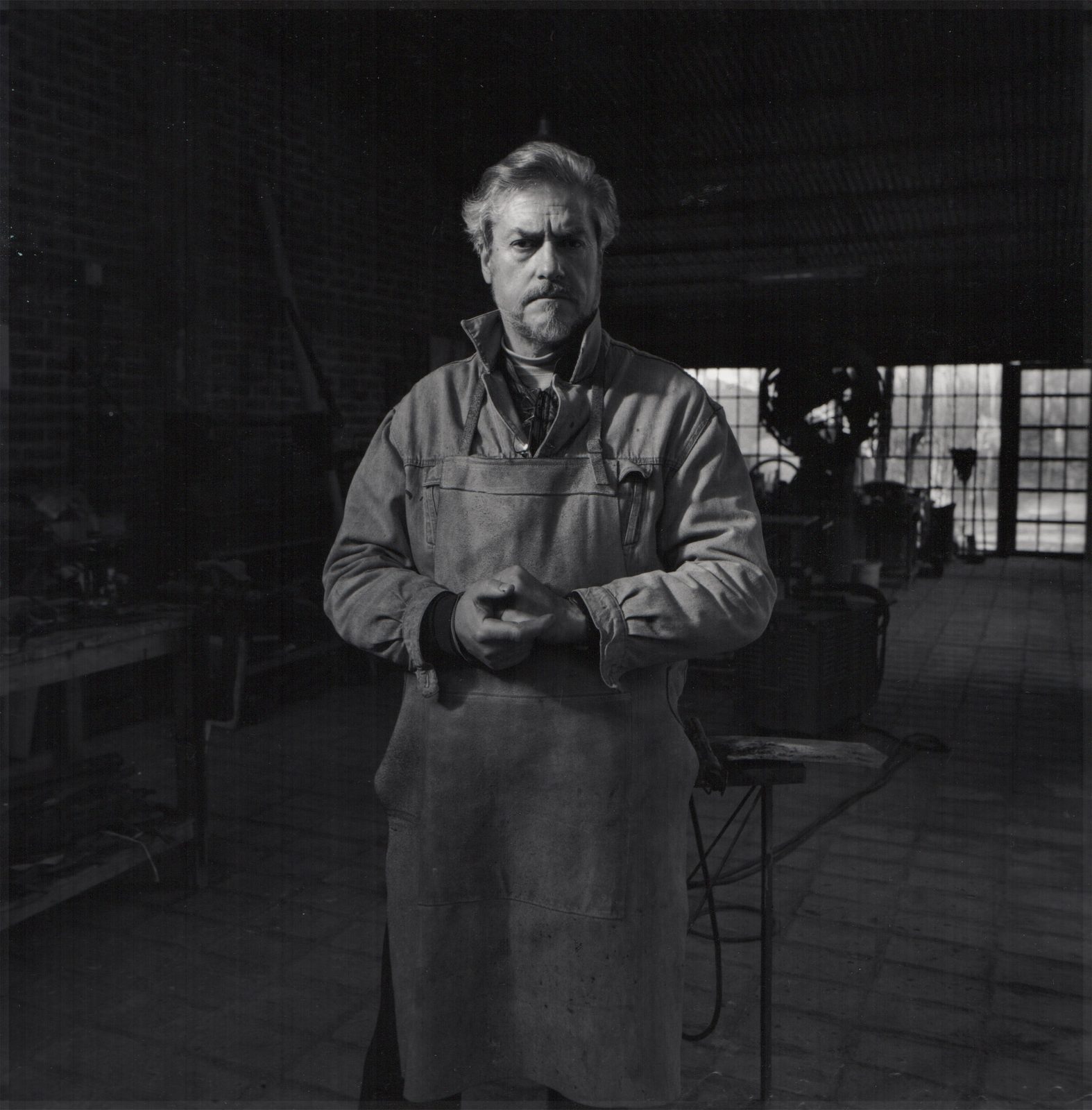 Retrato de Roberto Rosas con guardapolvo de trabajo, de pie en su taller