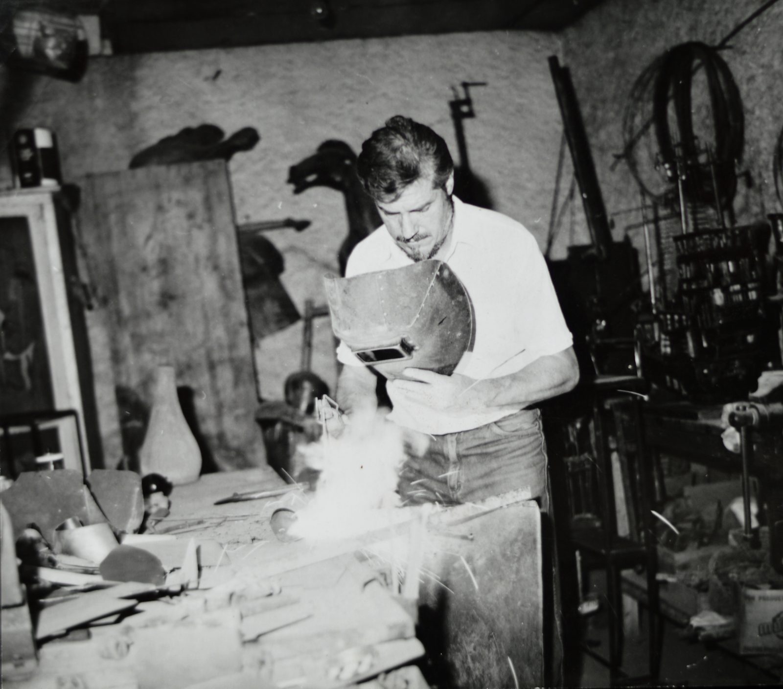 Roberto Rosas soldando una pieza de hierro en su taller, con chispas saltando